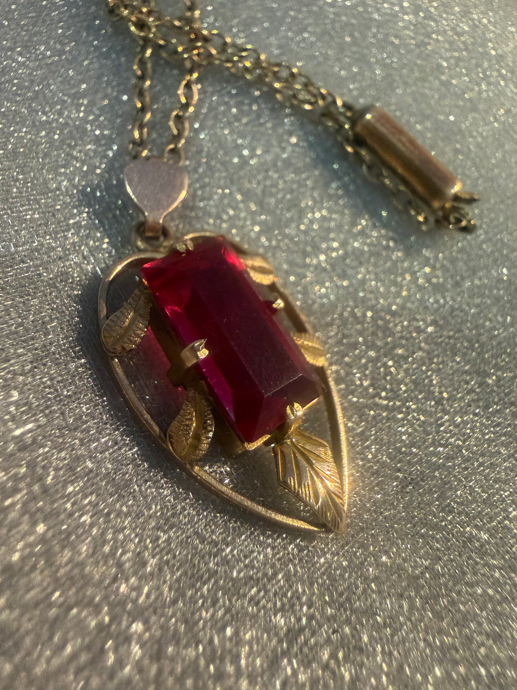 Vintage Lustre 9ct gold pendant, crimson stone in engraved leaf setting, close-up